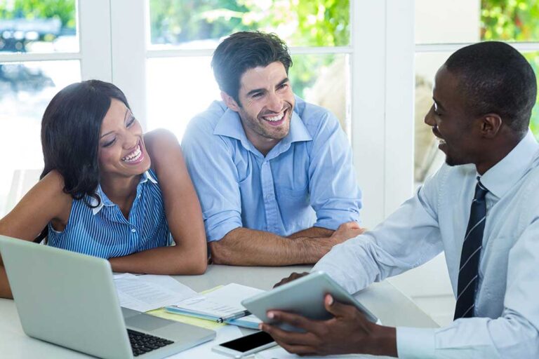 A young couple reviews home inspection documents with an inspector in a cozy living room.